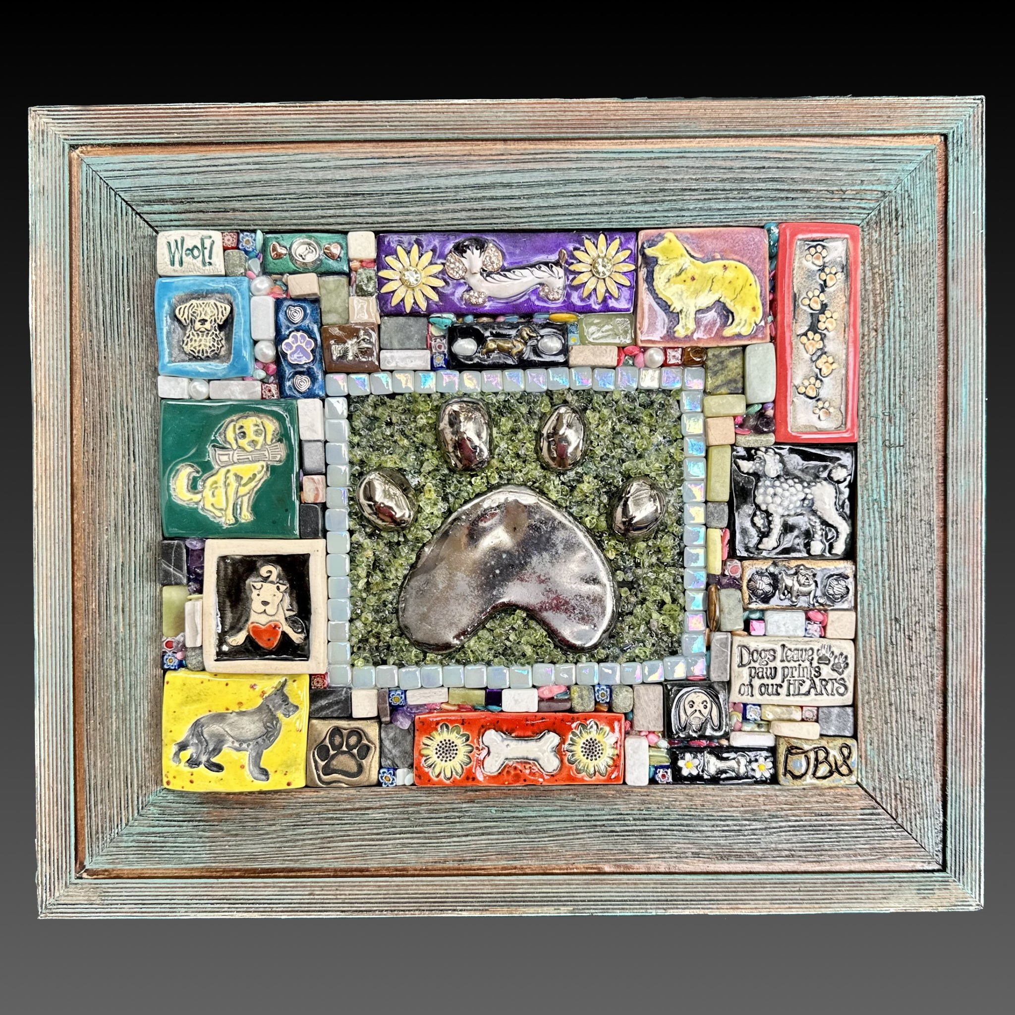 Clay mosaic artwork with a hand-sculpted clay paw print surrounded by dog themed clay tiles with a variety of colors and breeds. Great unique gift idea for pet parent!